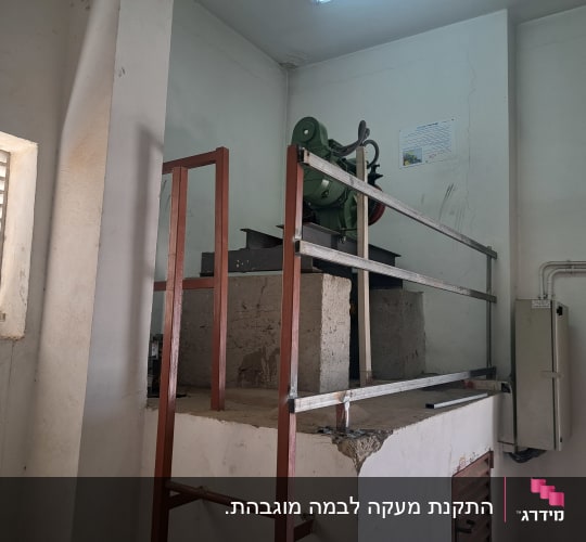 מעקה מתכת סביב מכונה על במה מוגבהת